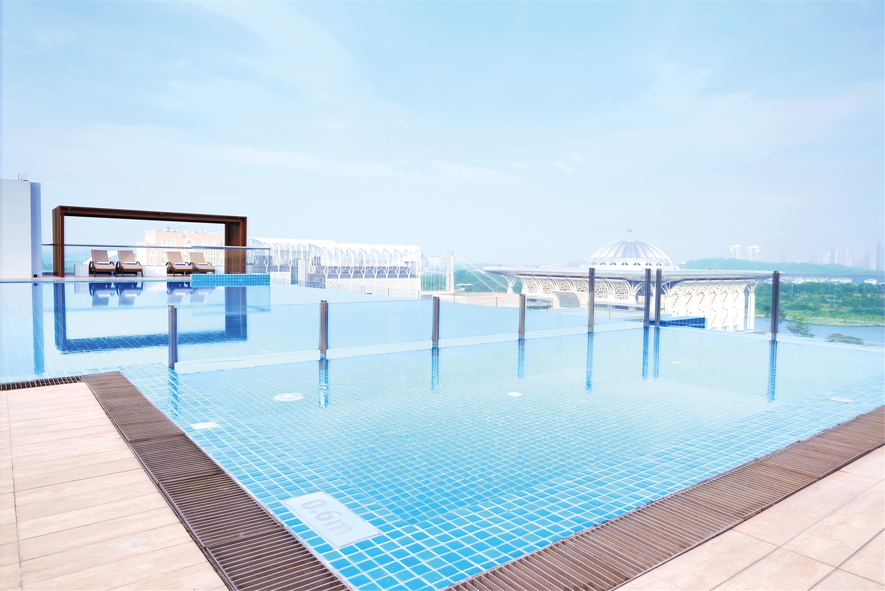 Dorsett Putrajaya Hotel Exterior photo The photo shows a modern infinity pool situated on a rooftop. The pool features clear blue water and is surrounded by a glass railing, enhancing the view. In the background, there are cityscape elements and buildings visible, indicating an urban sett