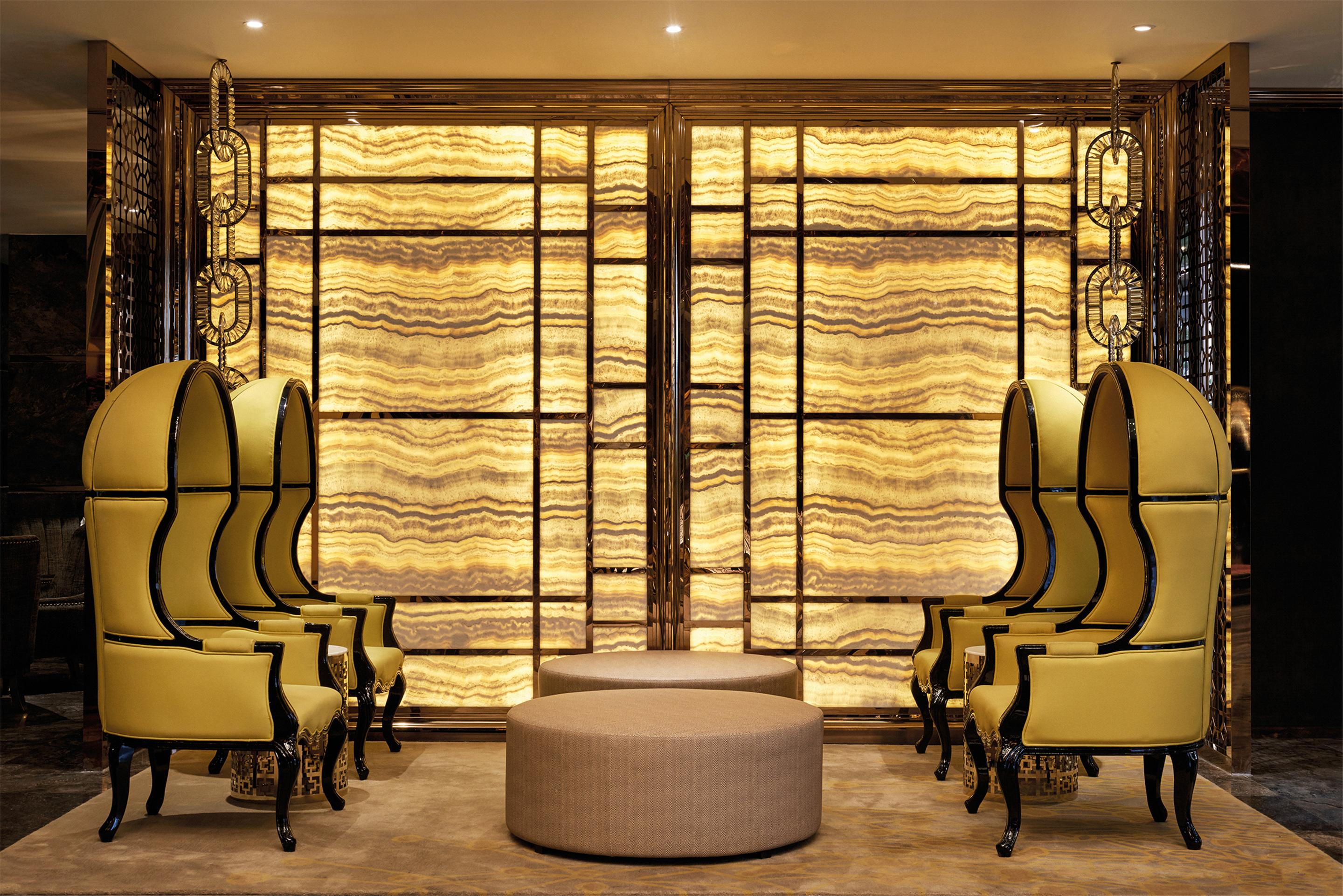 Dorsett Putrajaya Hotel Exterior photo The photo shows an elegant interior space featuring two sets of distinctive yellow armchairs with tall backs, arranged symmetrically. In the center, there is a round, low table that complements the seating area. The backdrop consists of a large, text