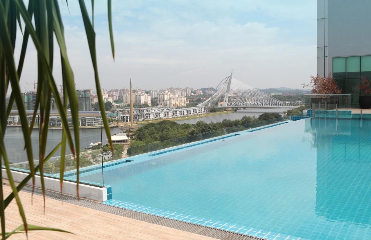 Dorsett Putrajaya Hotel Exterior photo The photo shows a beautiful pool area with a stunning view. In the foreground, there is an infinity pool that creates a seamless edge with the landscape beyond. The water in the pool reflects the sky, and the overall setting appears modern and serene