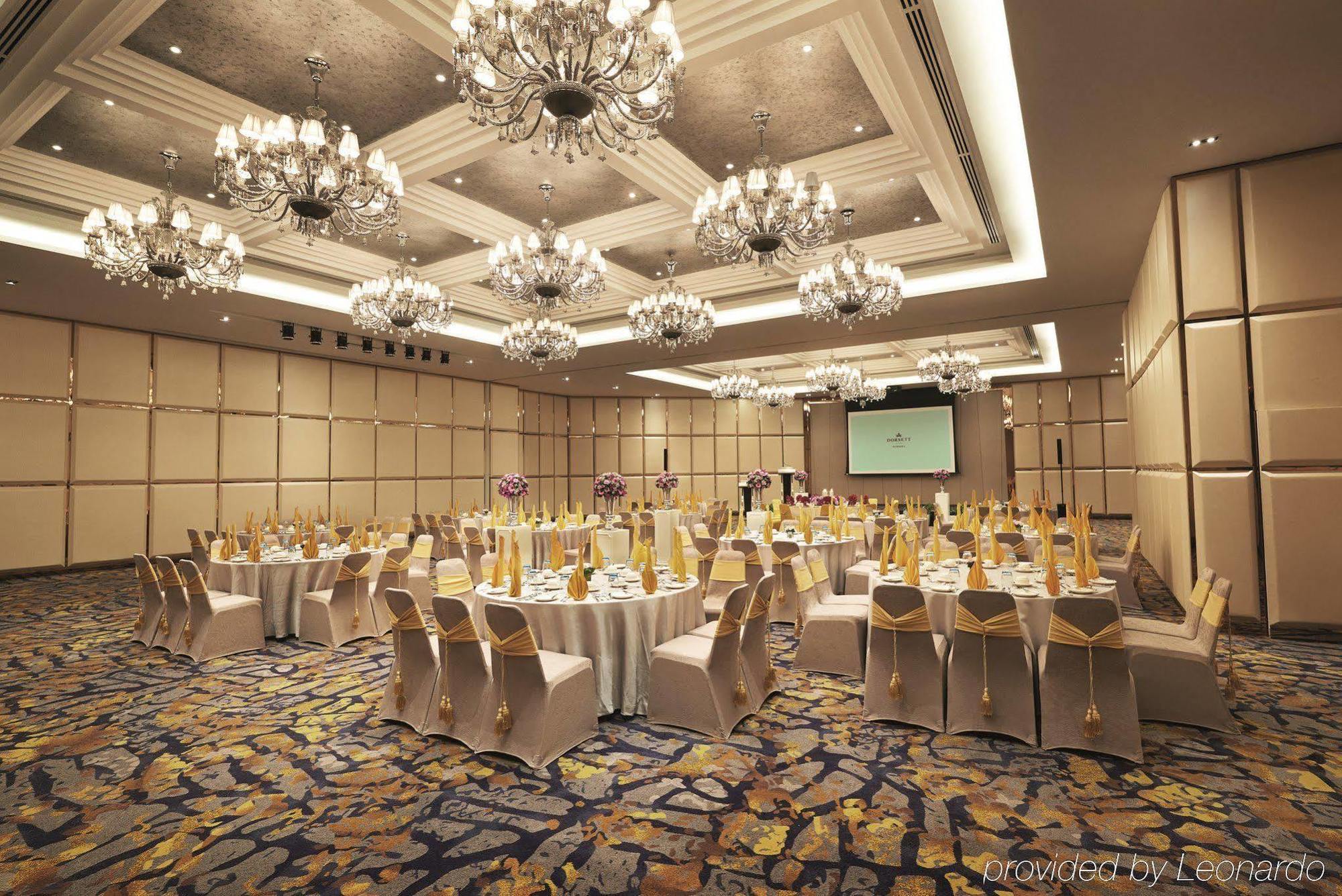 Dorsett Putrajaya Hotel Exterior photo The photo depicts an elegant banquet or conference room setup. It features multiple round tables, each covered with white tablecloths and adorned with gold decorations, suggesting a formal event. The chairs are also draped with golden sashes. The roo