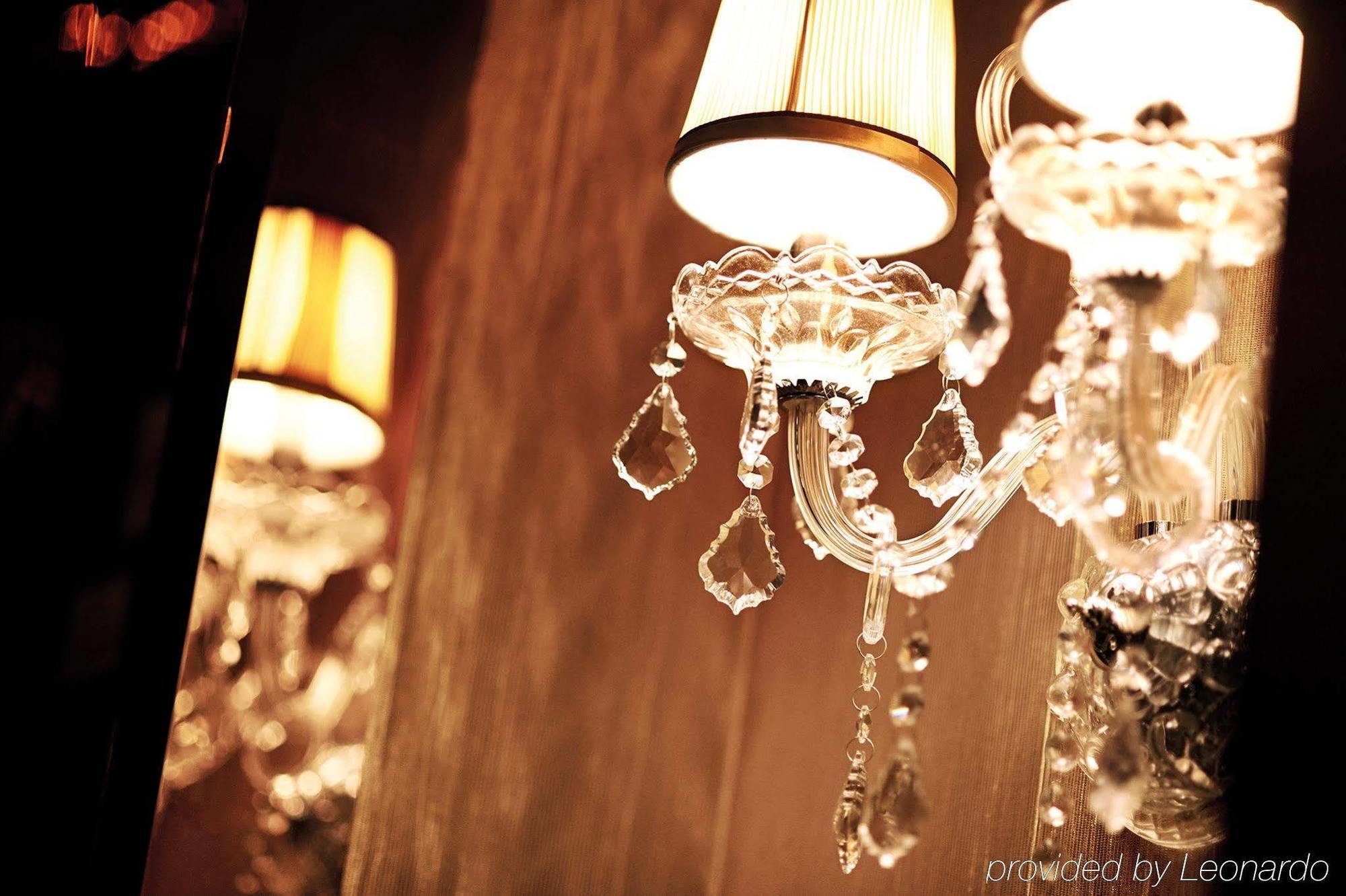 Dorsett Putrajaya Hotel Exterior photo The photo shows a decorative wall sconce, featuring an ornate design with clear crystals and a lampshade. The sconce has elegant arms adorned with hanging crystals that catch the light, creating a shimmering effect. Its warm glow adds a sophisticated