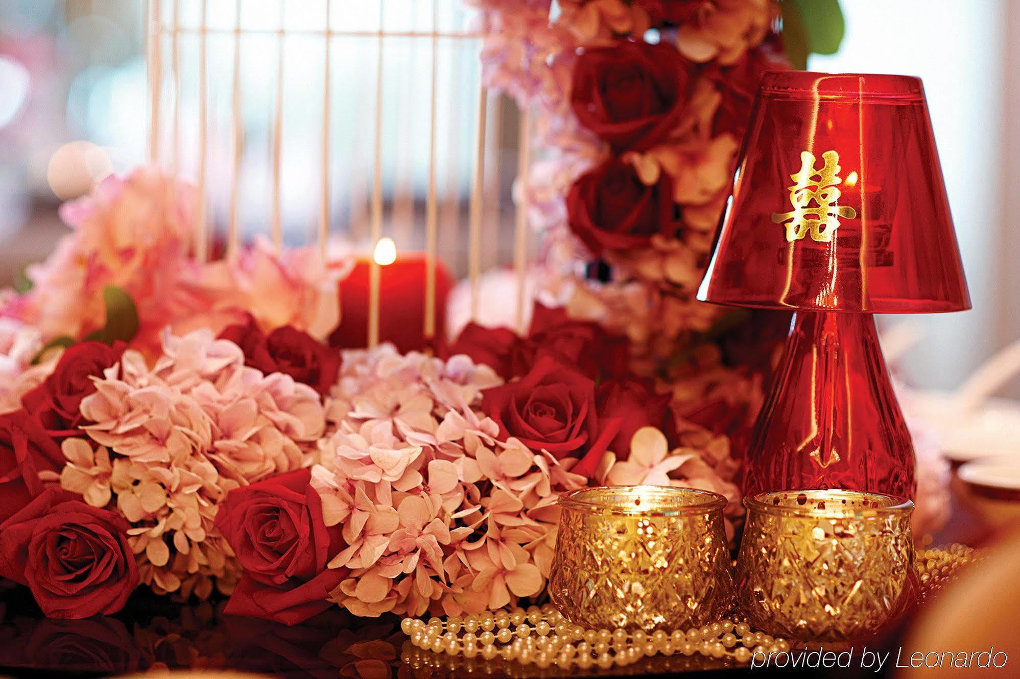 Dorsett Putrajaya Hotel Exterior photo The photo features a beautiful arrangement that includes a mix of floral elements such as pink and red roses, along with other delicate flowers. In the center, there are decorative items like a shiny red vase or lamp with a traditional symbol on it, 