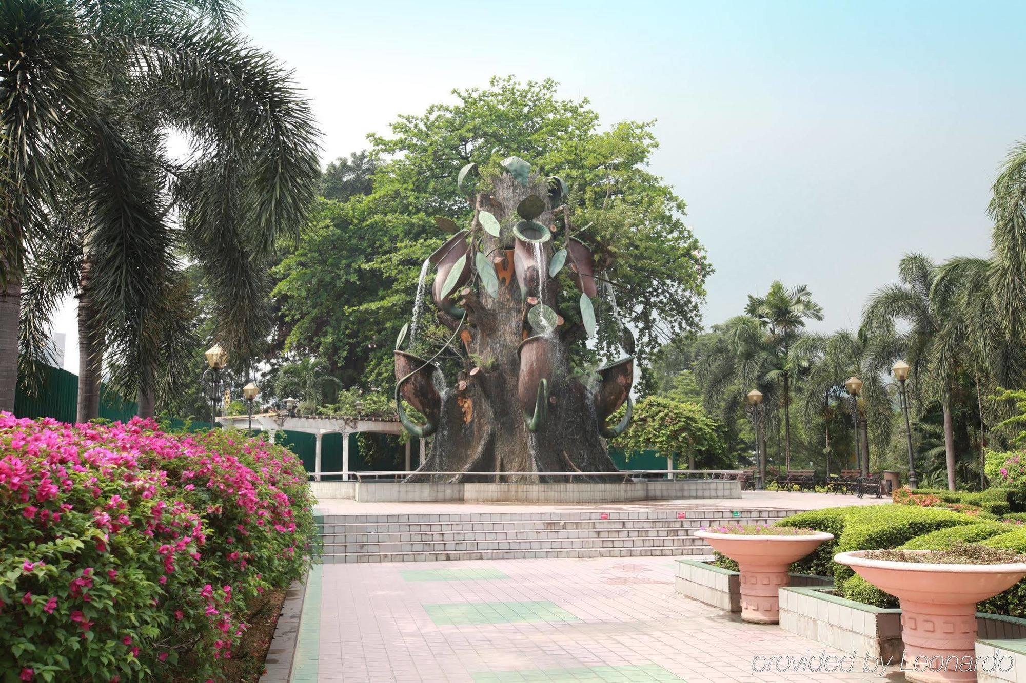 Dorsett Putrajaya Hotel Exterior photo The photo shows a park setting featuring a large, artistic water fountain that resembles a stylized tree or plant. The fountain has metallic and leafy elements, giving it a unique and modern appearance. Surrounding the fountain are lush green trees a