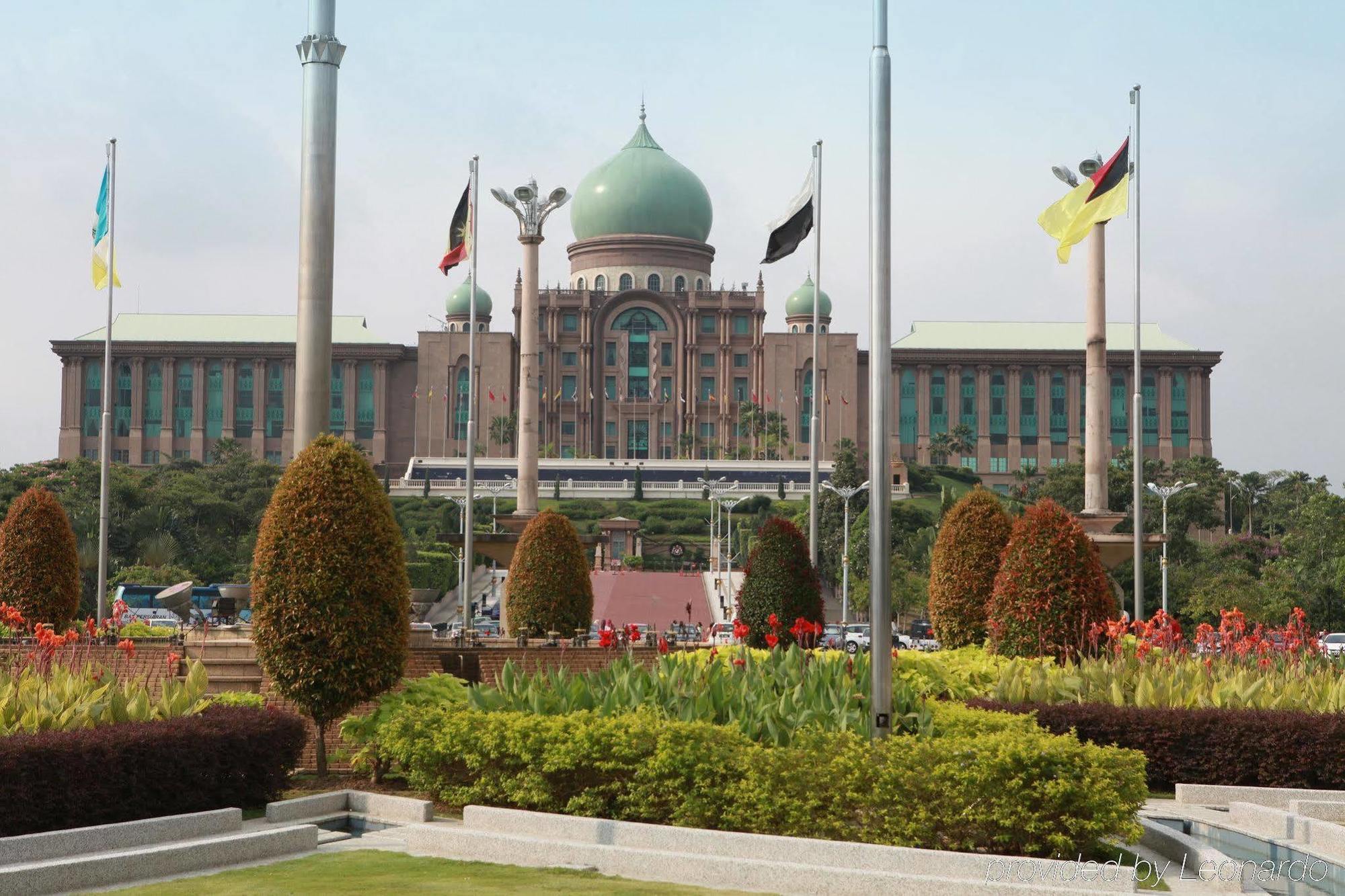 Dorsett Putrajaya Hotel Exterior photo The photo depicts a large, impressive building with a distinctive dome at the top. This structure is likely surrounded by well-maintained gardens featuring various plants and flowers. In the foreground, there are neatly arranged flower beds and bushe